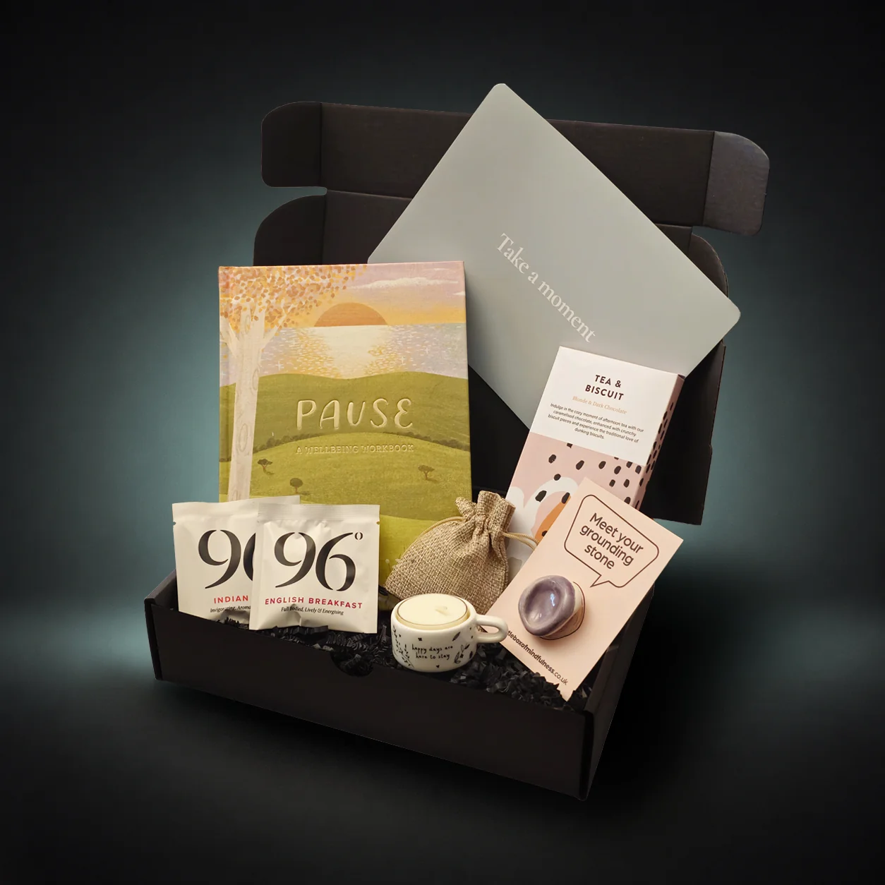 Your Little Mindfulness Box open to show a 'Pause. You are safe, you are capable, you are enough' message inside the lid, a welcome booklet and a mindfulness thumb stone